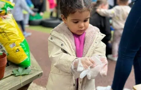 Nursery child putting on rubber gloves