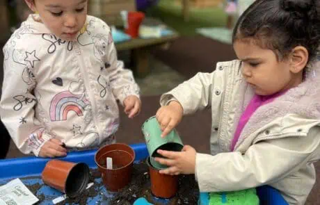 Nursery children planting seeds in soil